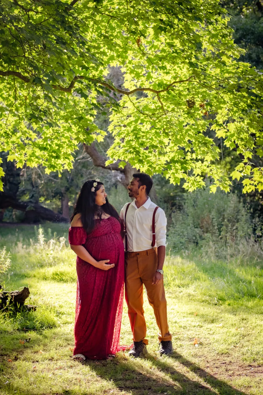 Pregnant woman and her husband in a park, enjoying warm weather and taking a maternity photoshoot