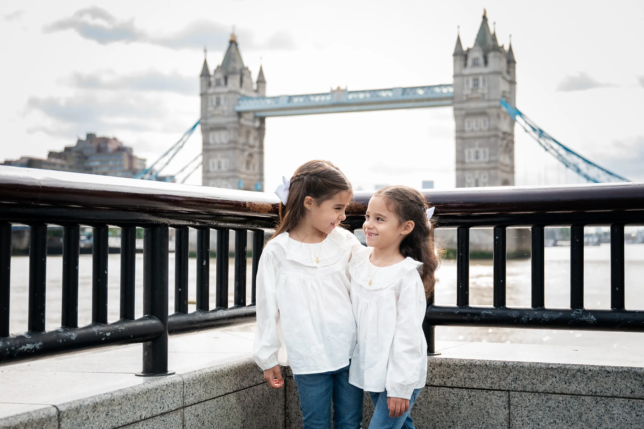 Two sisters looking at each other in-front of the Tower Bridge in London