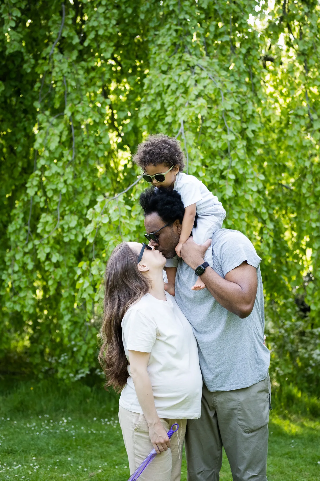 Family of three, soon to be four in a park, enjoying time together while taking a photoshoot