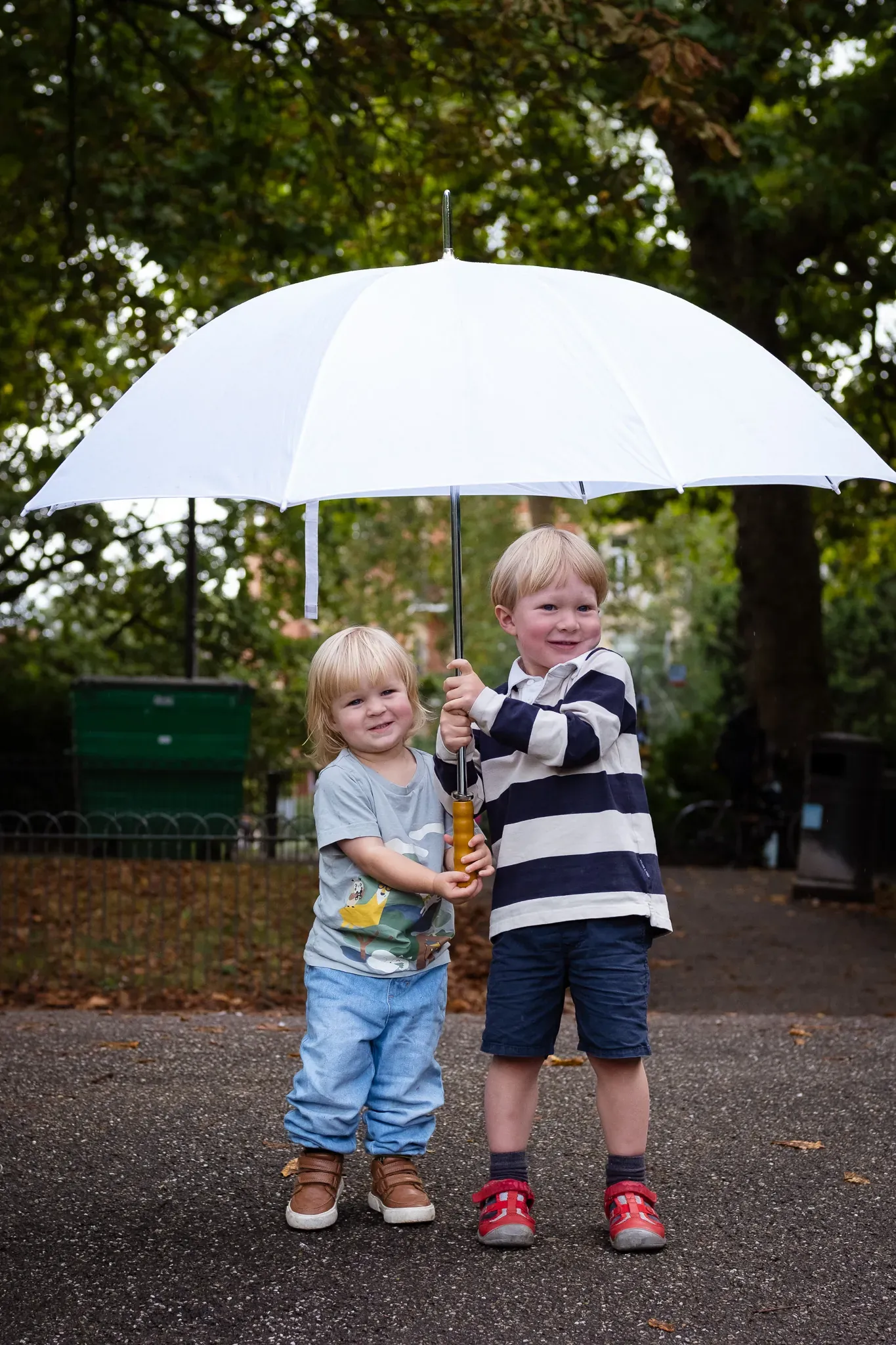 Brother and sister with a white umbrella, posing for a family photoshoot