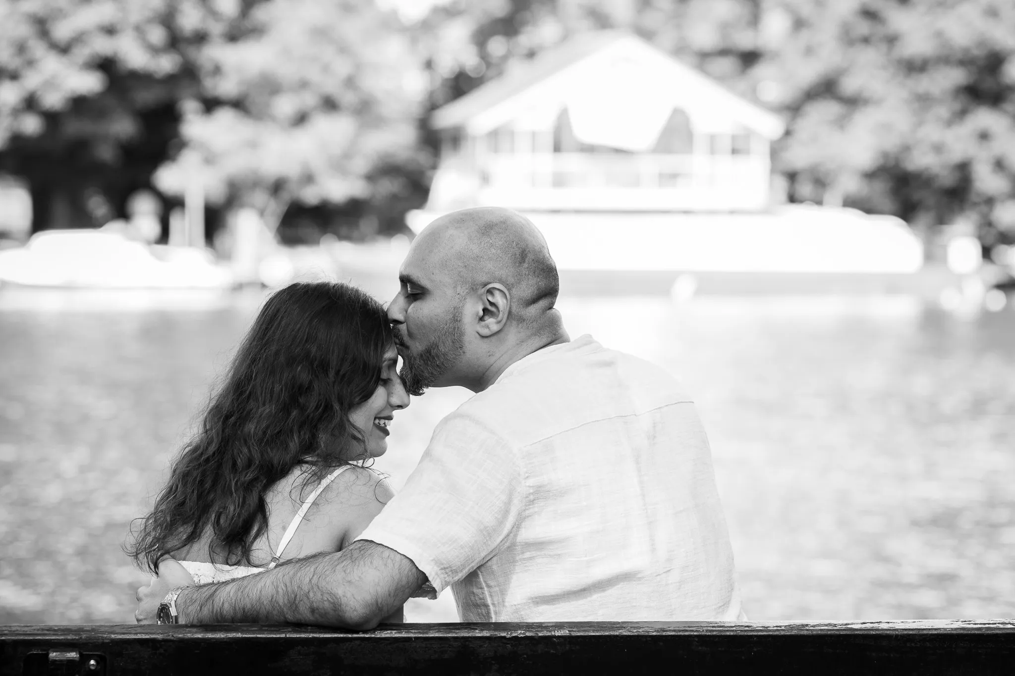 Couple sitting on a bench, the man kissing his lovely wife