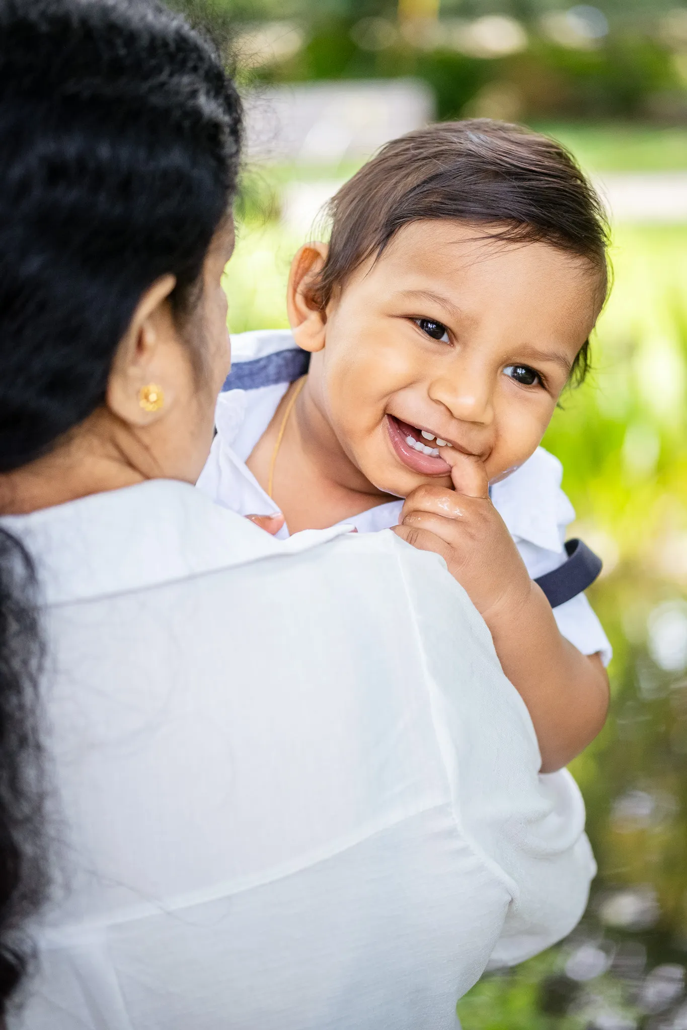 Little baby boy smiling, with his finger in the mouth.