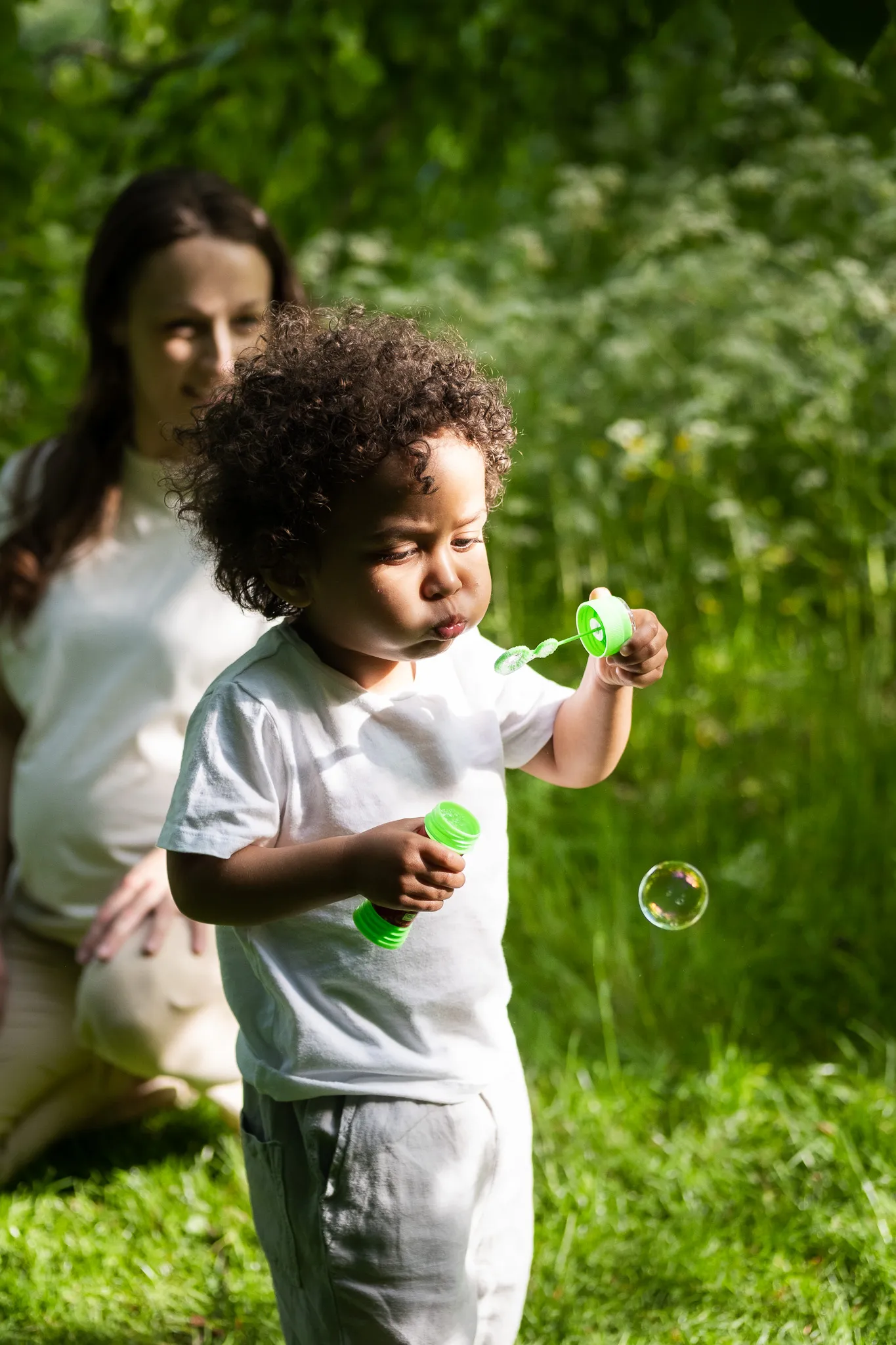 Little boy, doing soap bubbles in a park for a family photoshoot with his family