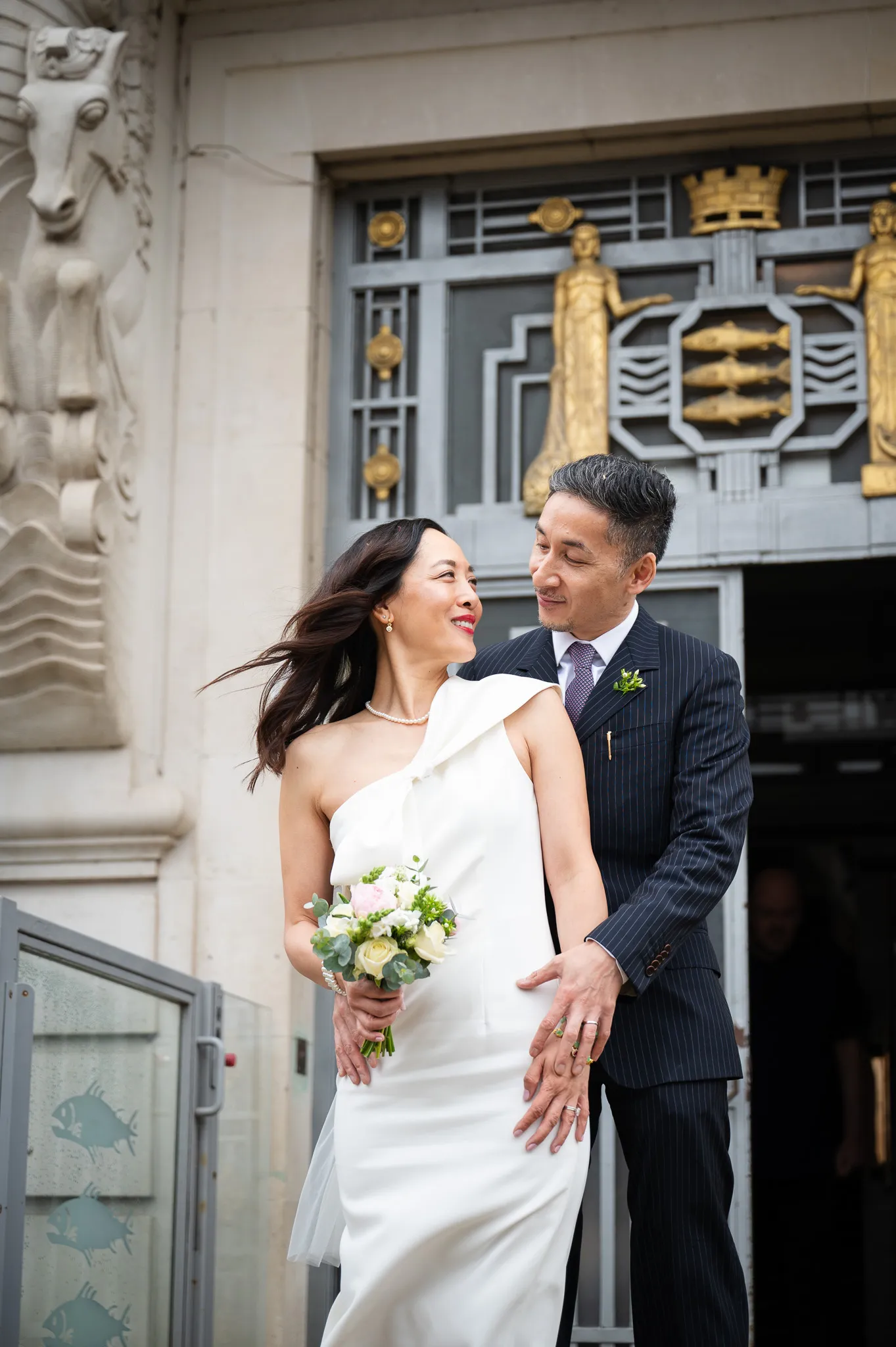 A joyful couple in wedding attire smiles while embracing