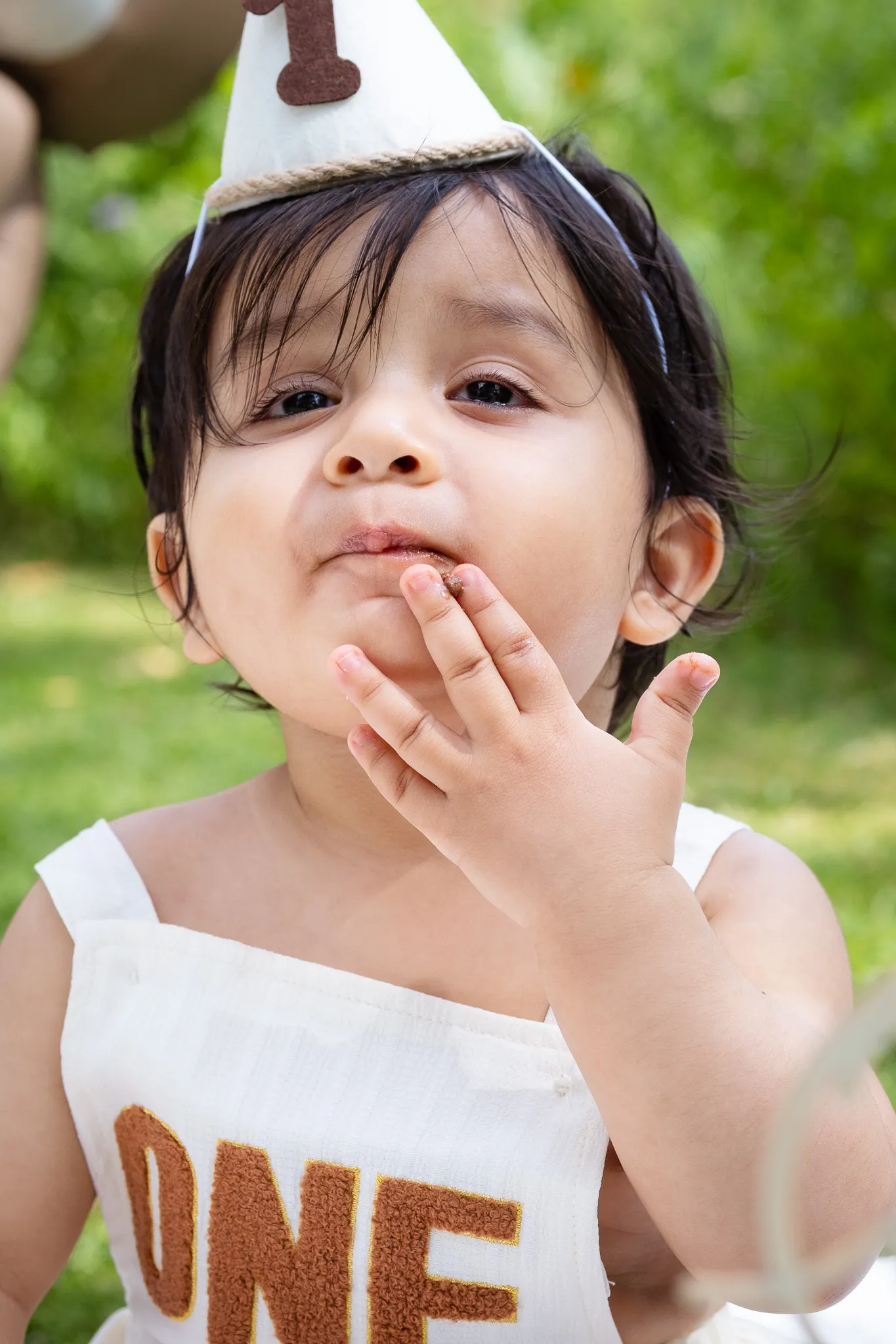 Little baby boy's first birthday photoshoot in a park, cake smash on a picnic, birthday decoration, balloons