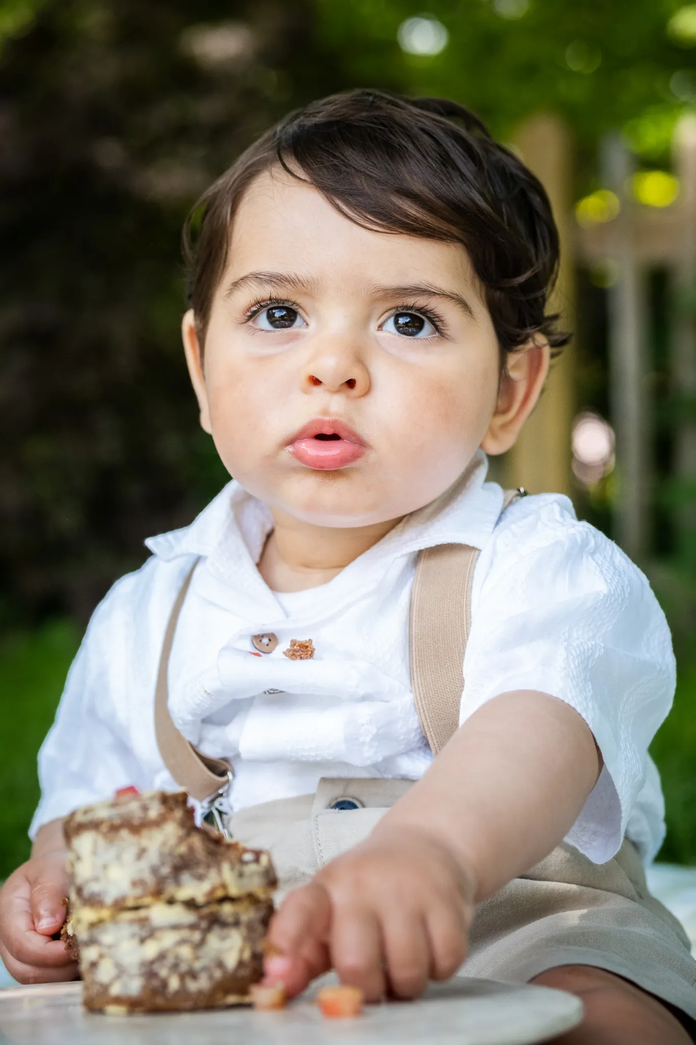 Little boy for his first birthday for a outdoor cake smash photoshoot in the park on a picnic blanket