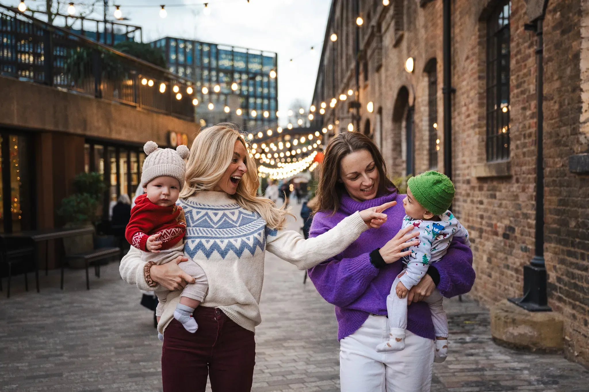 Two mothers and their children smiling and looking at each other