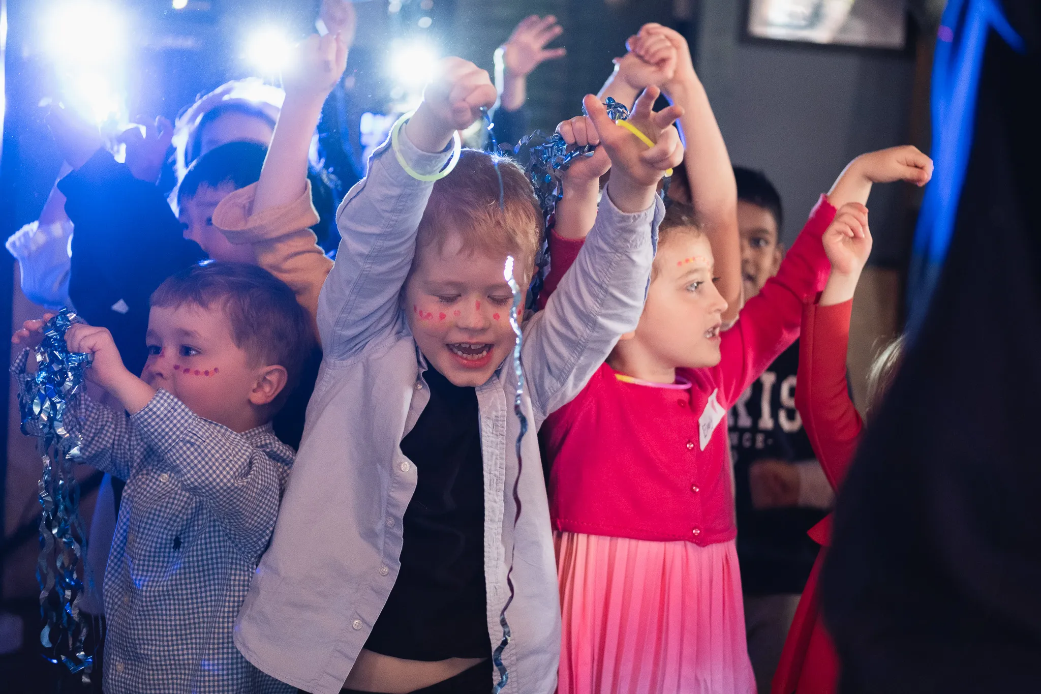 Group of kids dancing on fun music, having a bright light behind them and having a good time on a birthday party