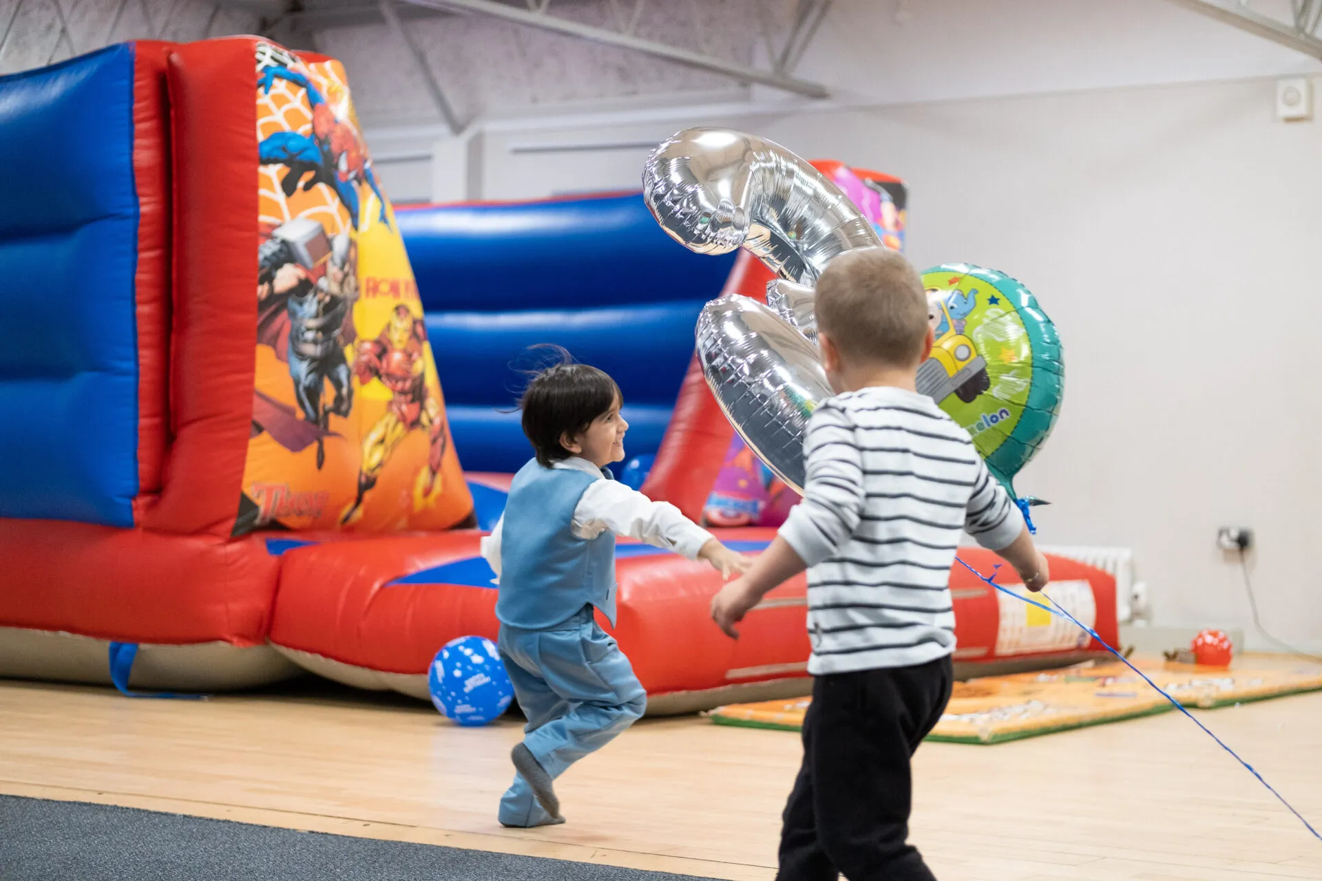 Two little boys running around a balloon
