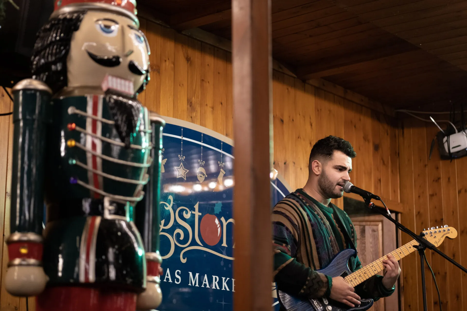 A man who is performing and playing a guitar on a christmas market