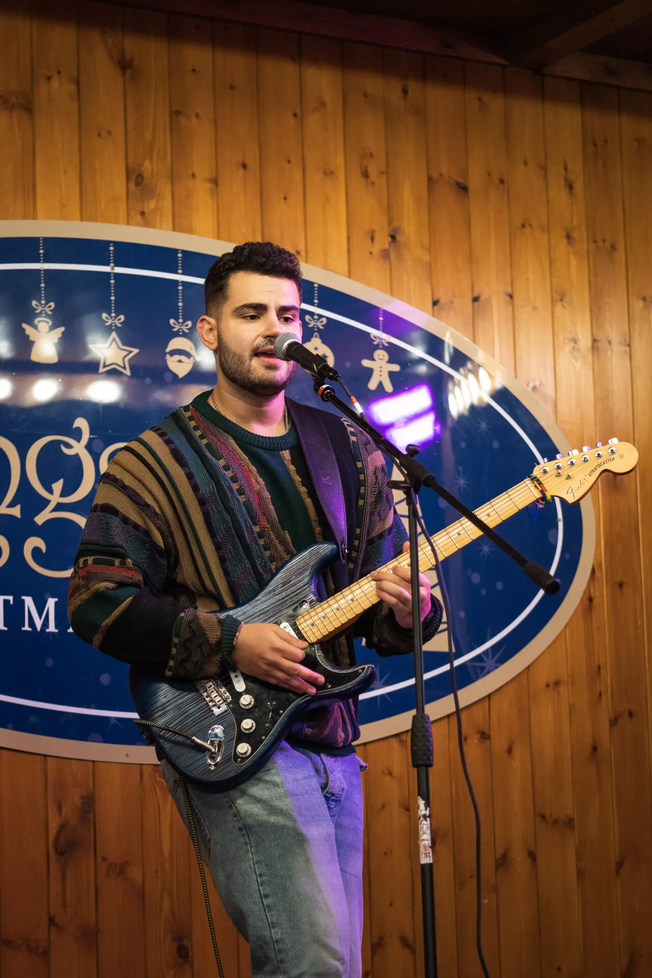 A man who is performing and playing a guitar on a christmas market