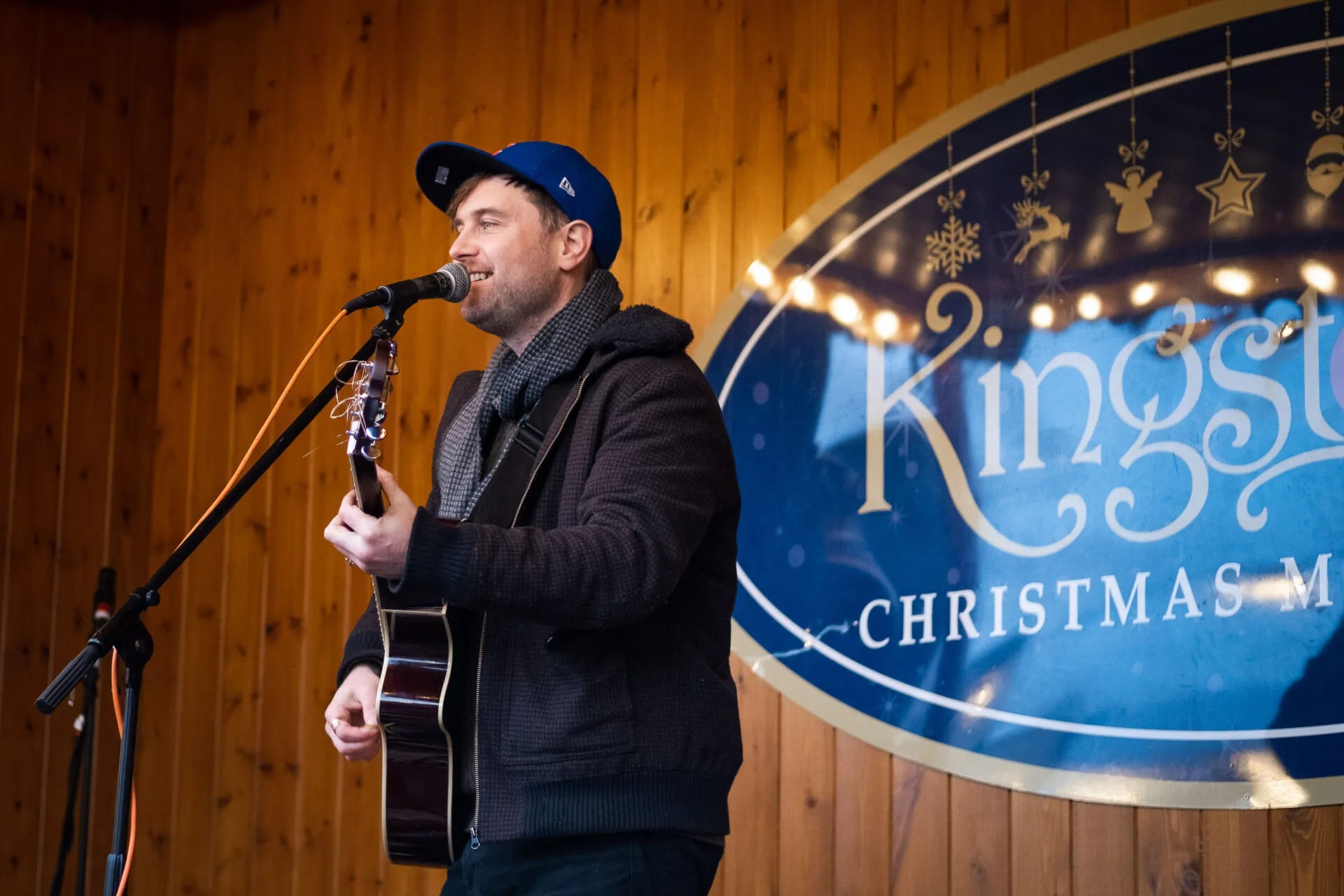 A man who is performing and playing a guitar on a christmas market