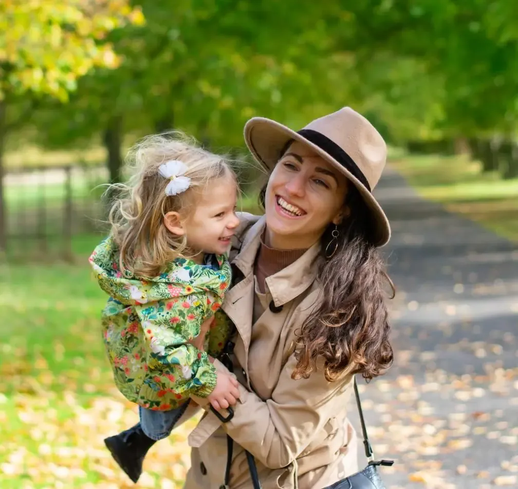 Mum laughing with her toddler daughter on an autumn walk in the park