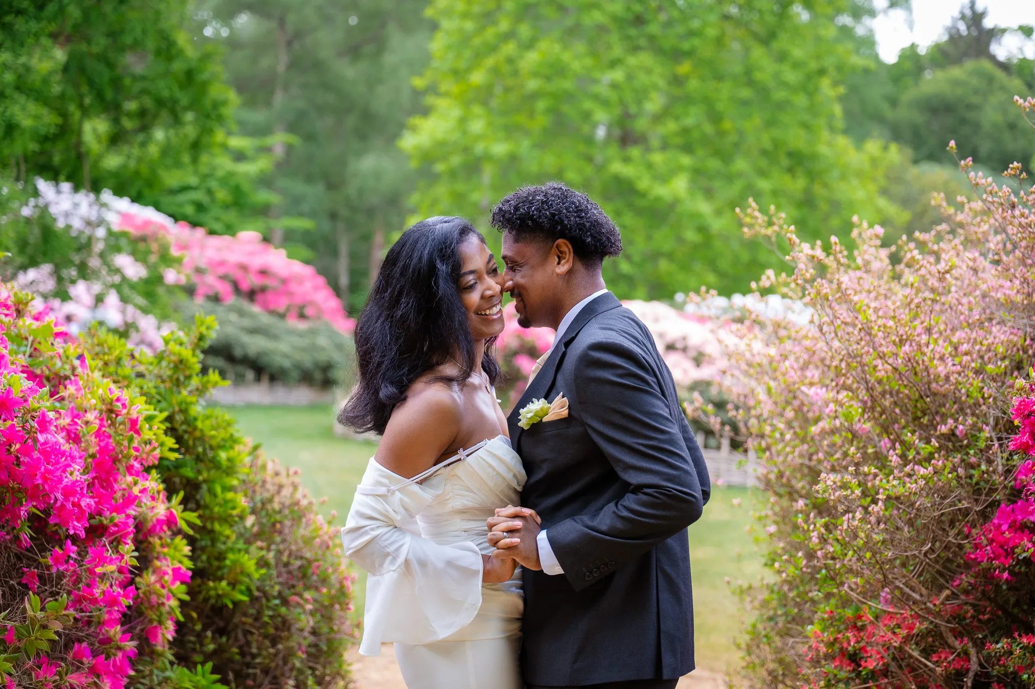 Couple laughing together in front of pink azalea bushes