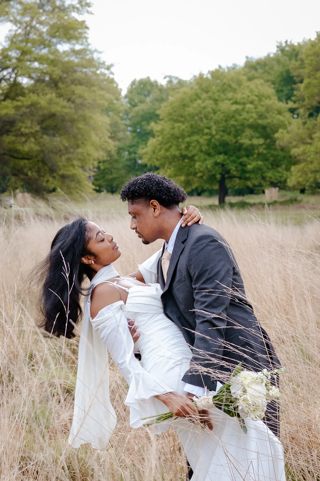 Groom dipping his bride for a kiss in a field of tall golden grass