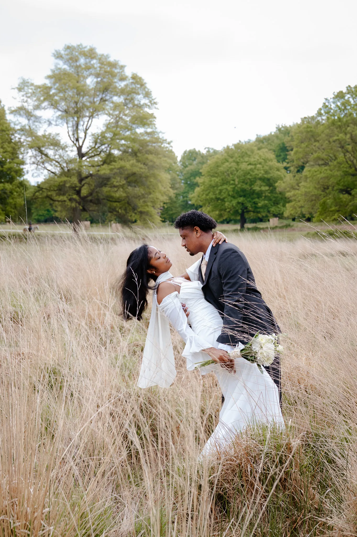 Groom dipping his bride for a kiss in the tall golden grass of Richmond Park