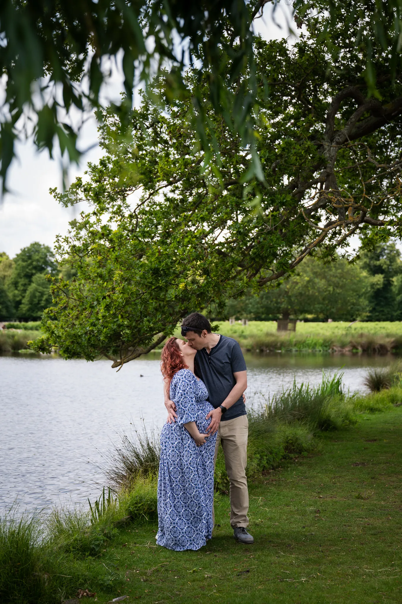 Dad-to-be kissing his pregnant partner by the river