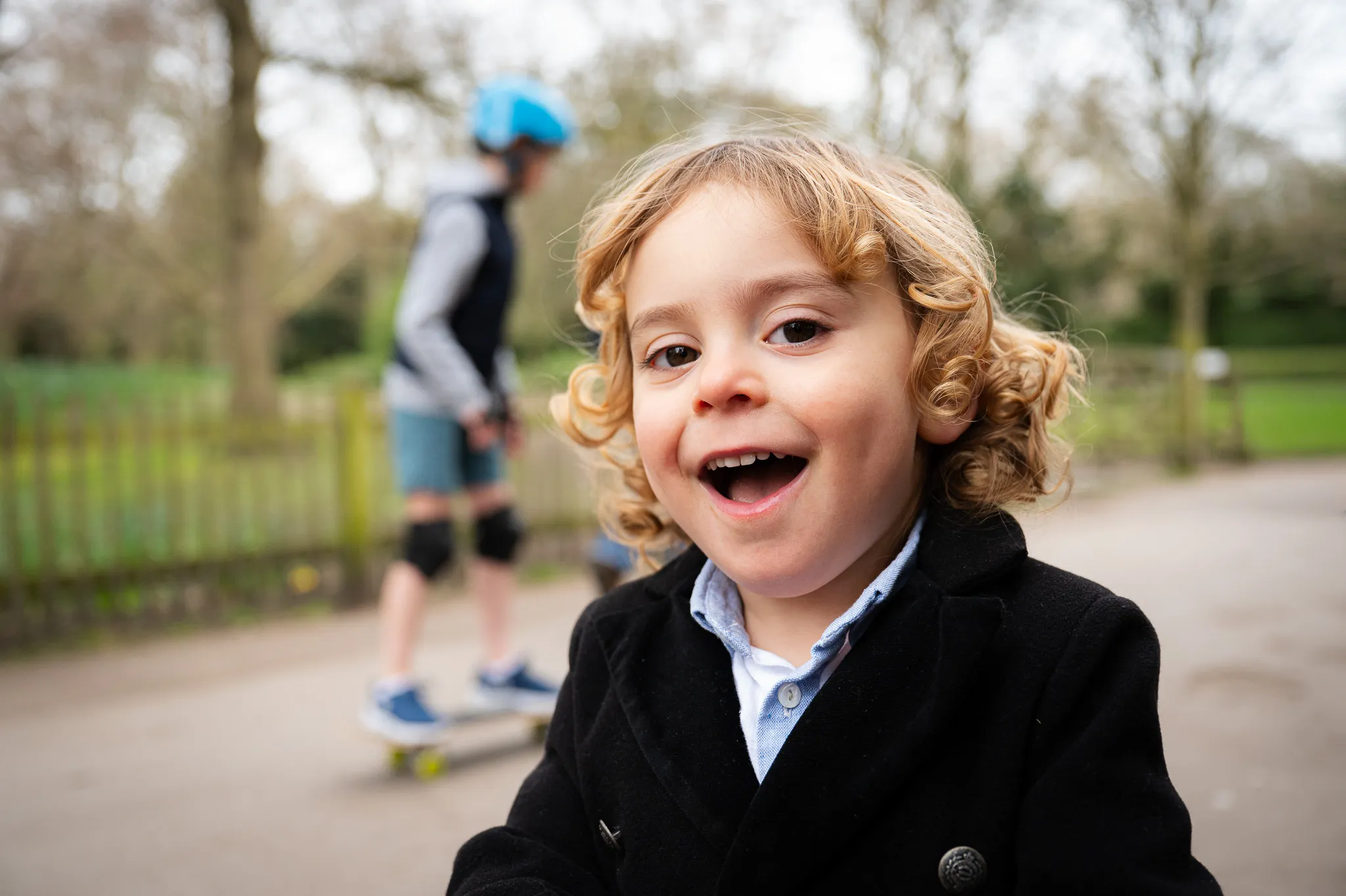 Curly-haired boy laughing on a park path