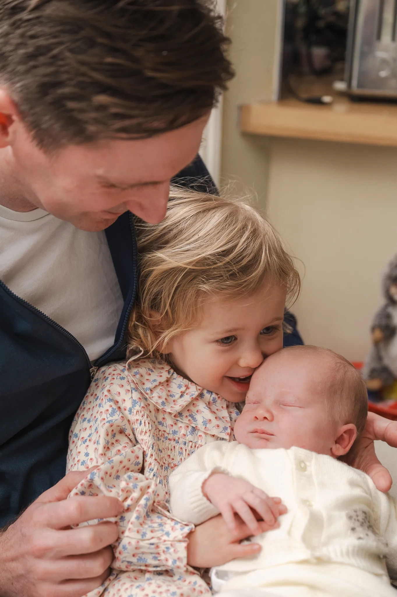 Dad and big sister snuggling the newborn baby at home