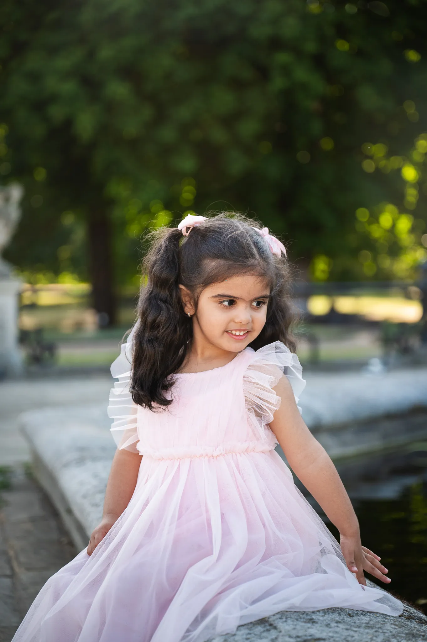 Little girl in a pink tulle dress with bows in her hair in the park
