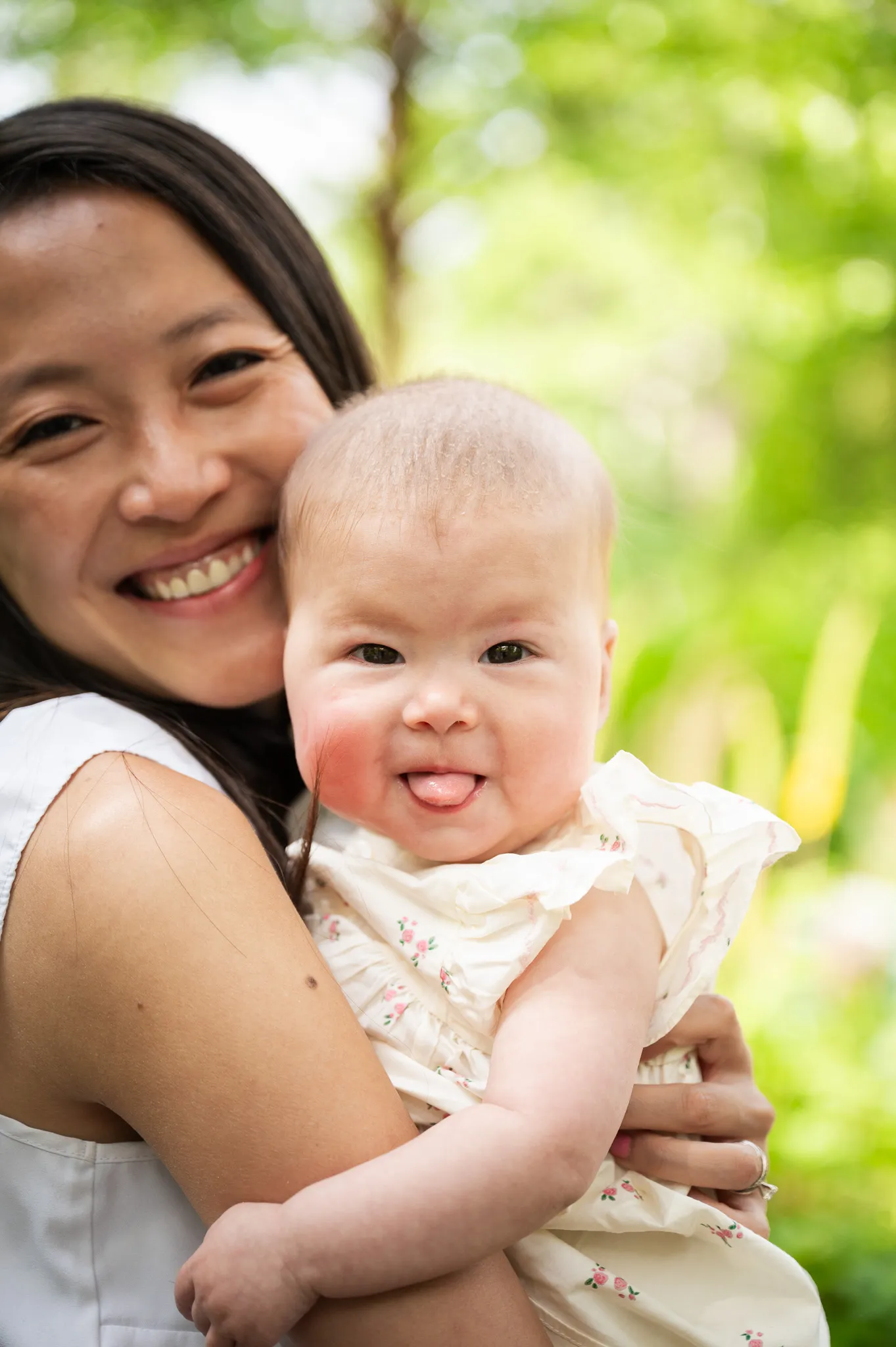 Smiling mum cheek to cheek with her baby sticking out her tongue