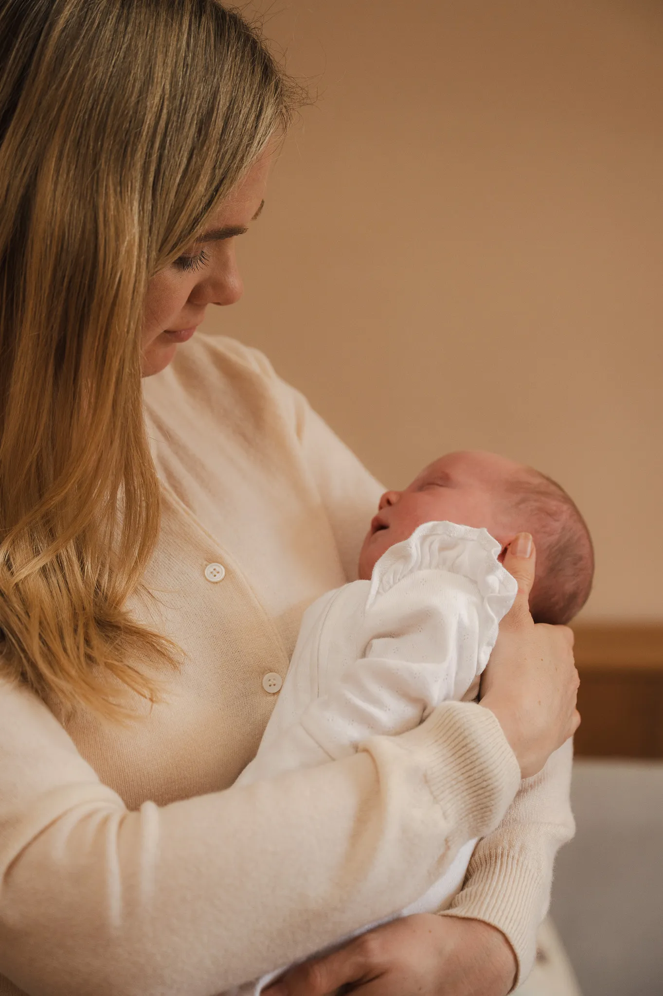 Mum gently cradling her sleeping newborn at home