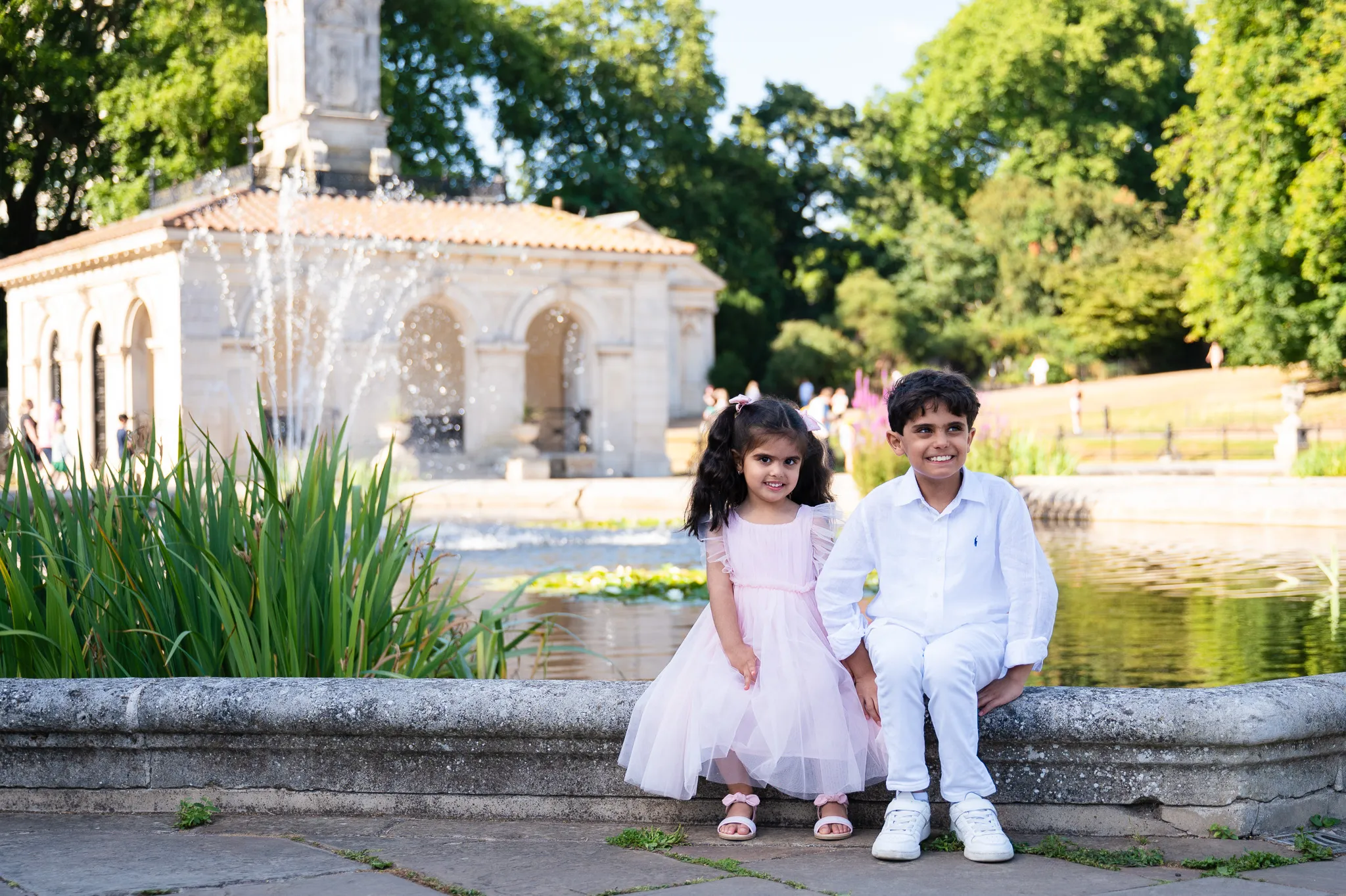 Brother and sister dressed in white standing by the Italian Gardens fountains