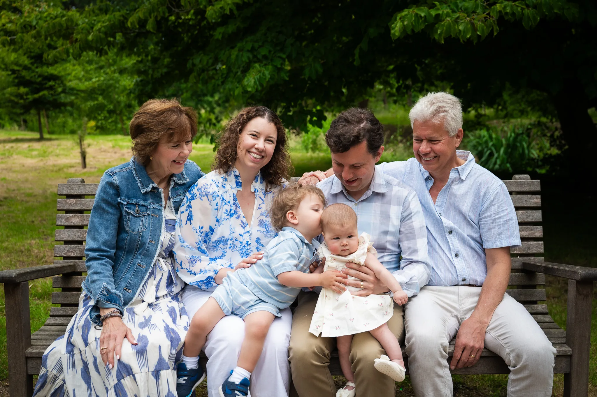 Three generations of a family smiling together on a park bench