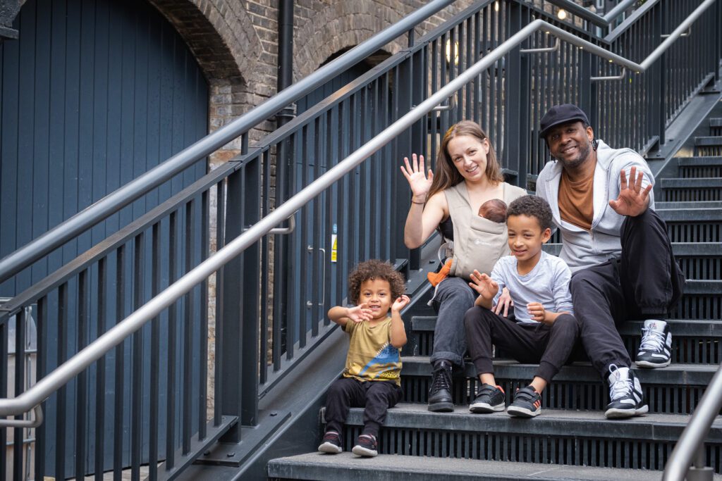 Family of five, waving and sitting on a stairs, enjoying time together, while taking a photoshoot with Mellsnap