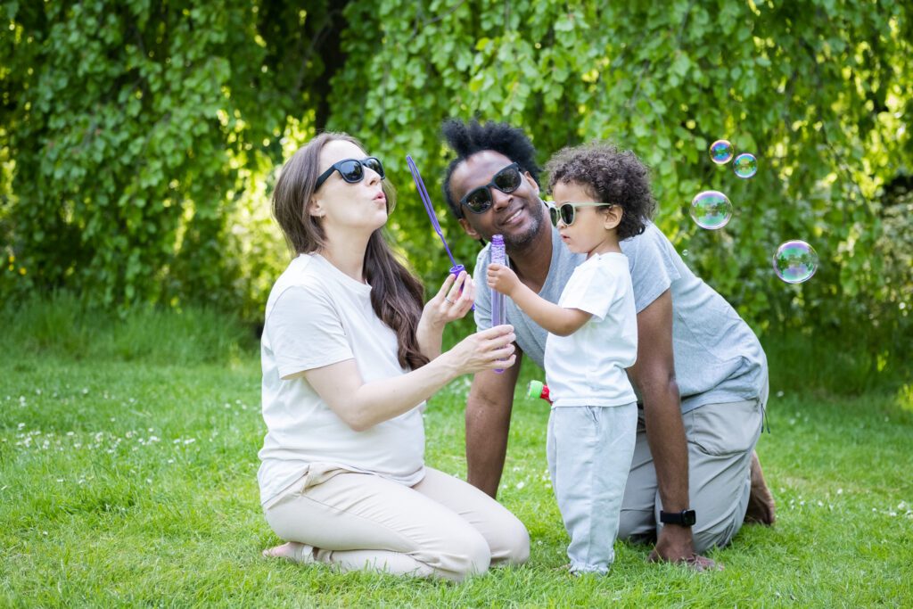 Family playing together in a park with soap balloons, posing for a quick photoshoot in the park 