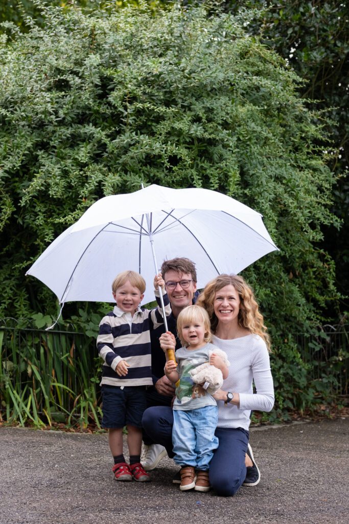 Smiling family of four, holding an umbrella, quick family outdoor photo session